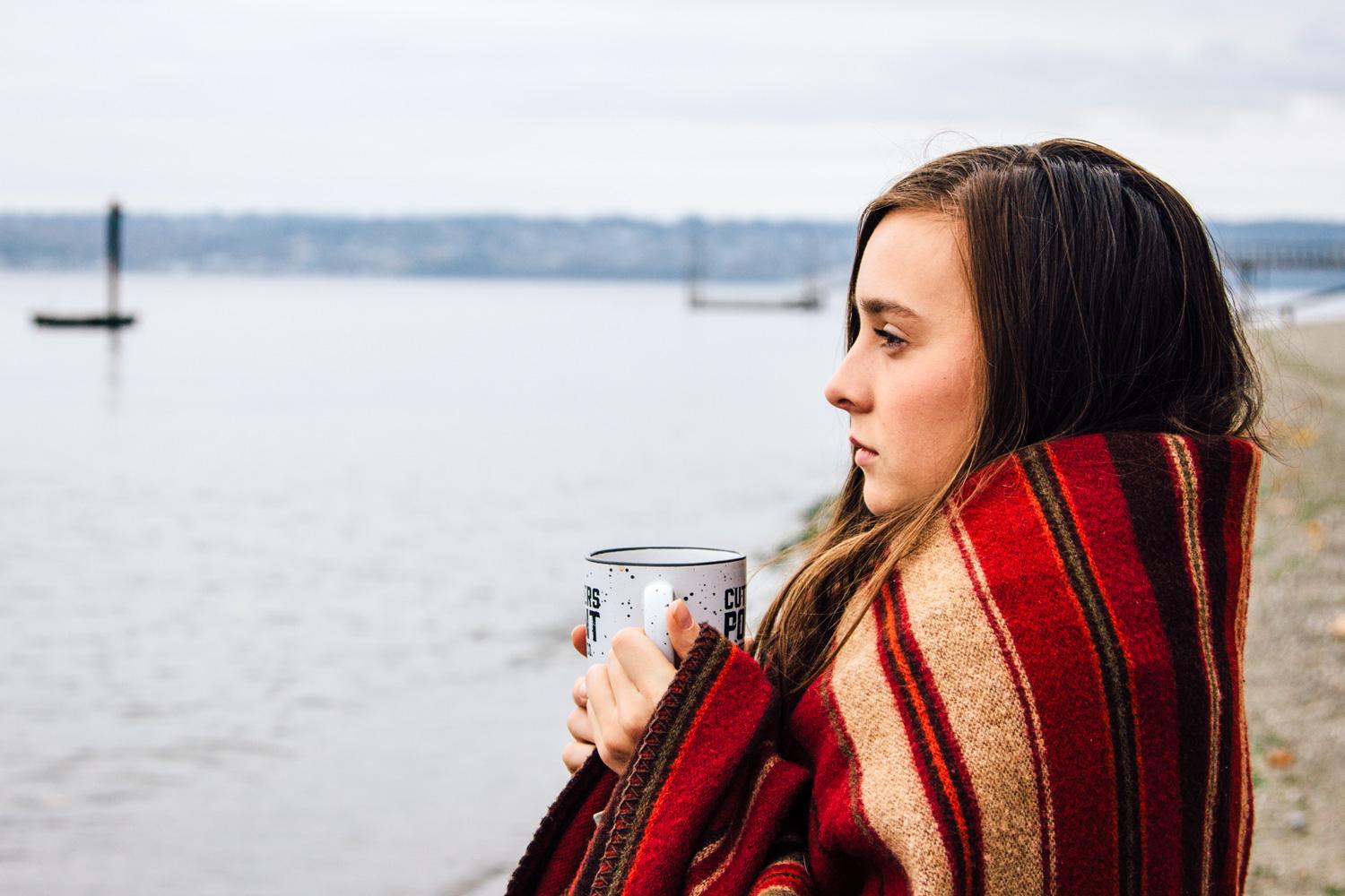 Young woman wrapped in a blanket looking at the Puget Sound