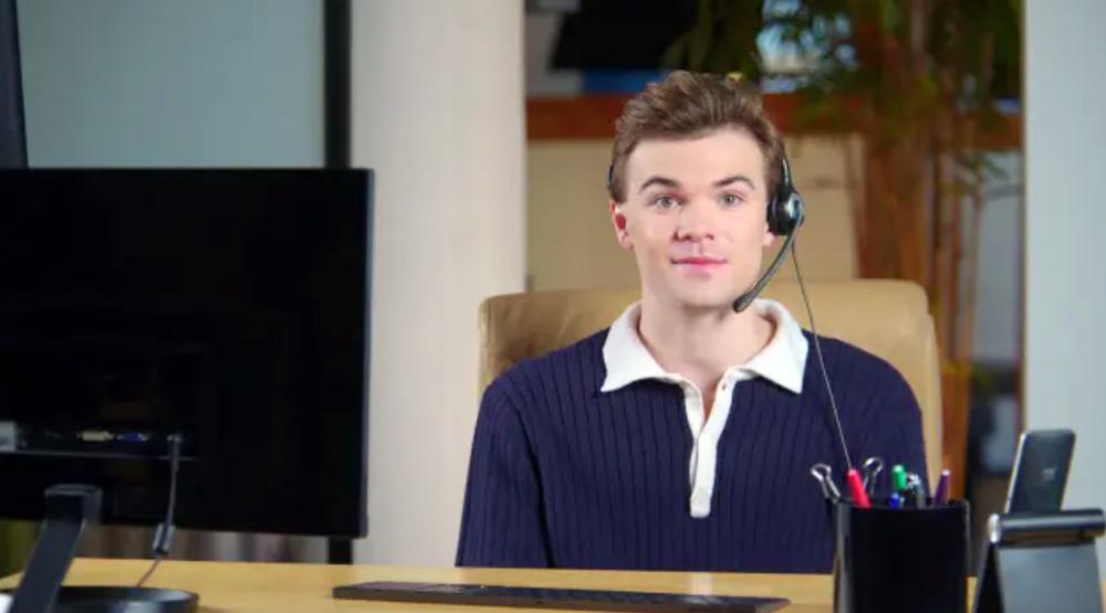 A young man at an office desk wearing a headset