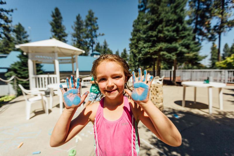 Girl showing her hands covered in blue paint